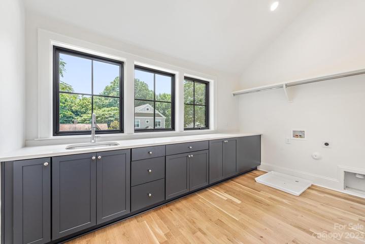 Enormous laundry room with sink, cabinets and quartz counterops