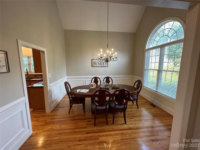 Formal dining room with vaulted ceiling, gleaming hardwoods, beautiful chandelier and huge palladium window.