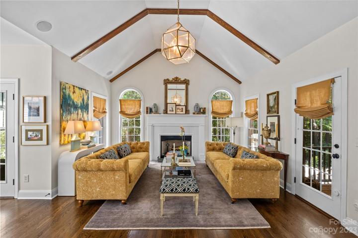 Family room, features a gas log fire place, cathedral ceilings outfitted with beams, floor to ceiling windows and access to the back patio.