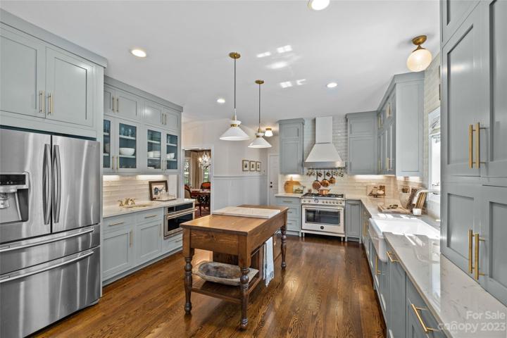 Double door stainless steel refrigerator, Circa lighting, Kitchen Aid Dishwasher, GE wall oven, oak wood floors.