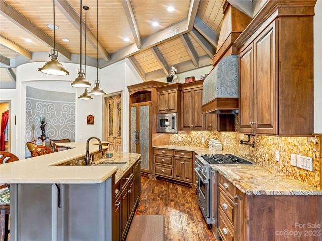From the glass tile backsplash to the high-end professional appliances to the artistic hood vent, to the Rainforest brown marble countertops, to the meticulous custom cabinetry, this kitchen absolutely glows from within~
