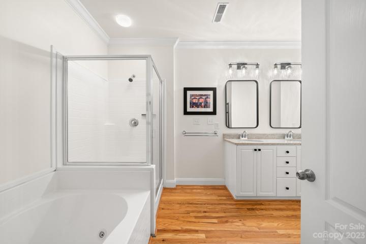 Warm hardwood floors continue into the bathroom with dual vanities, walk-in shower and tub.