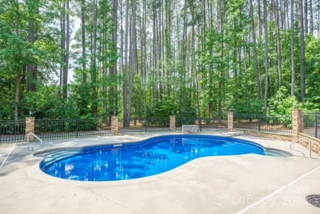 Beautiful pool and deck surrounded by wrought iron