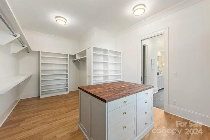 Primary closet features custom shelving and island