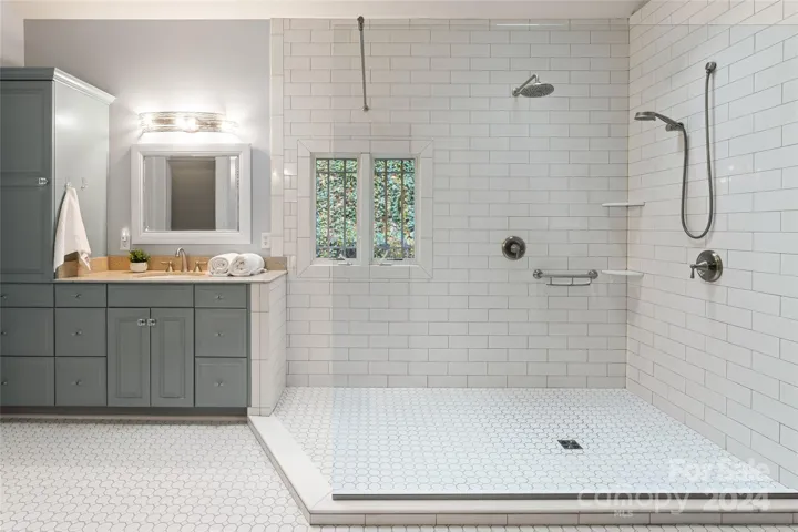 Tastefully updated primary bath with heated floors and spacious walk-in shower with multiple shower heads