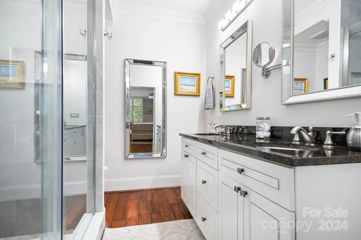 Renovated primary bathroom with dual sink vanity and newly tiled walk in shower.