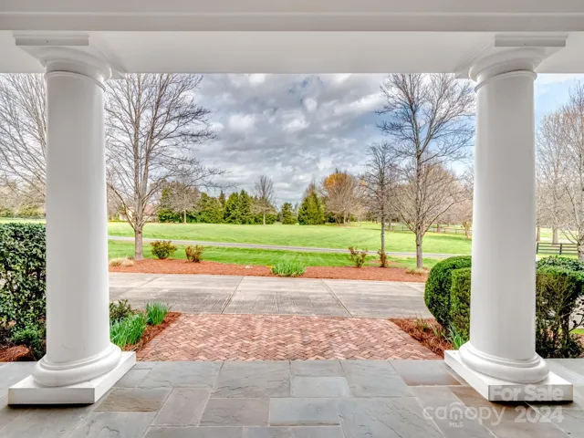 Beautiful view of herringbone pavers and greenscape in front of home