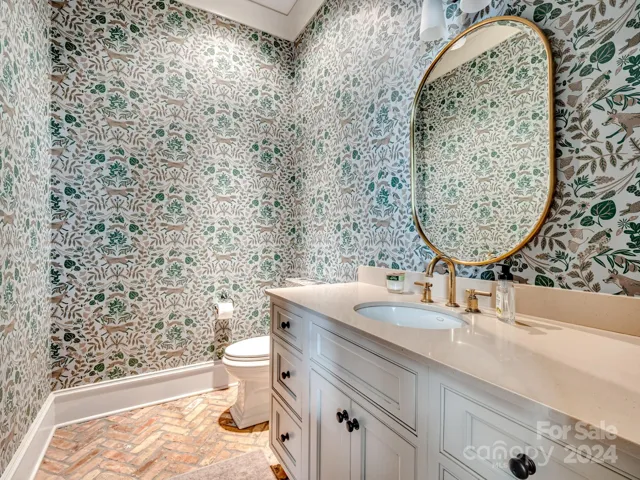 Beautiful powder room at rear entry with gorgeous wallpaper and brick flooring