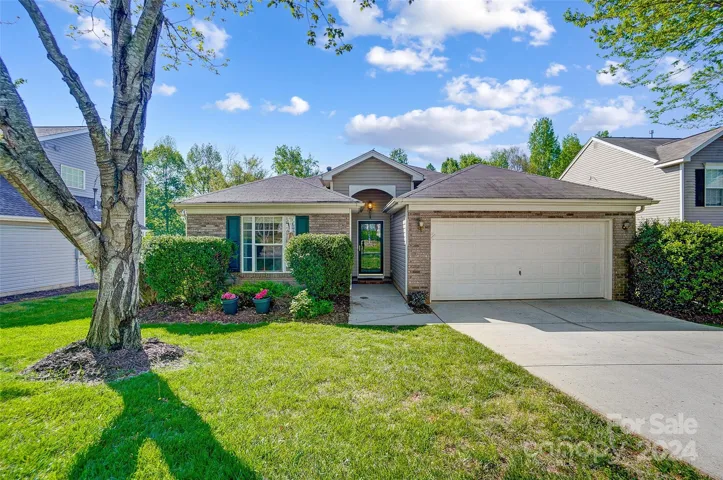 Front of home, mature tree, walkway and 2 car garage