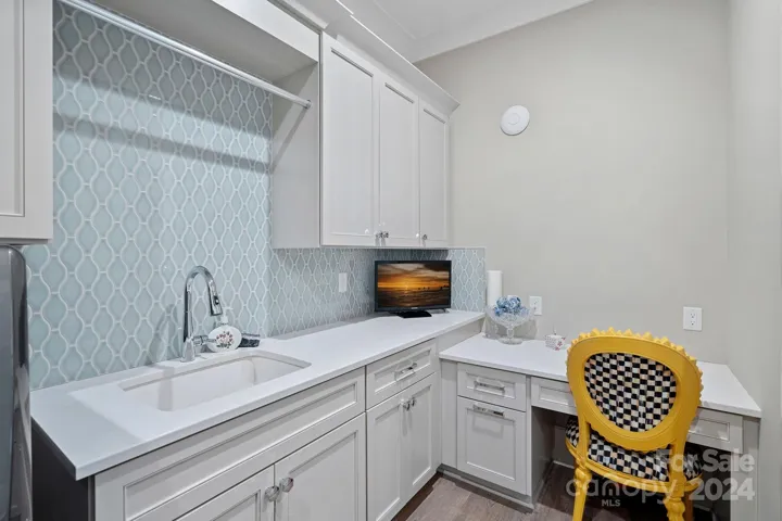 Laundry room features designer tile backsplash and built in desk area.