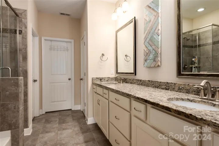 Primary bathroom with neutral colors, tile, walk in shower, garden tub, dual vanity and large walk in closet.