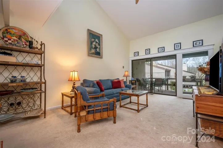 Living room with cathedral ceiling and the door leads out to covered deck