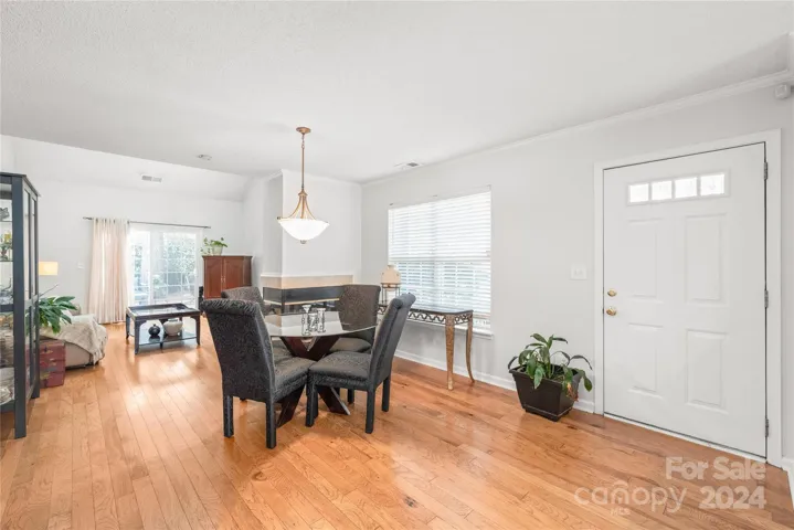 Spacious open floor plan adorned with hardwood flooring, crown molding, and abundant natural light.