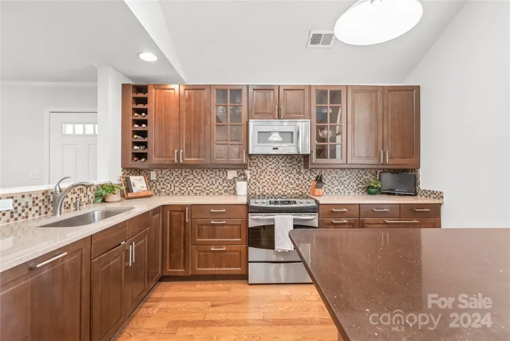 Discover culinary perfection in this renovated kitchen, boasting Silestone quartz countertops, pull-out drawers, a counter-depth refrigerator, expansive island, hardwoods and vaulted ceilings.