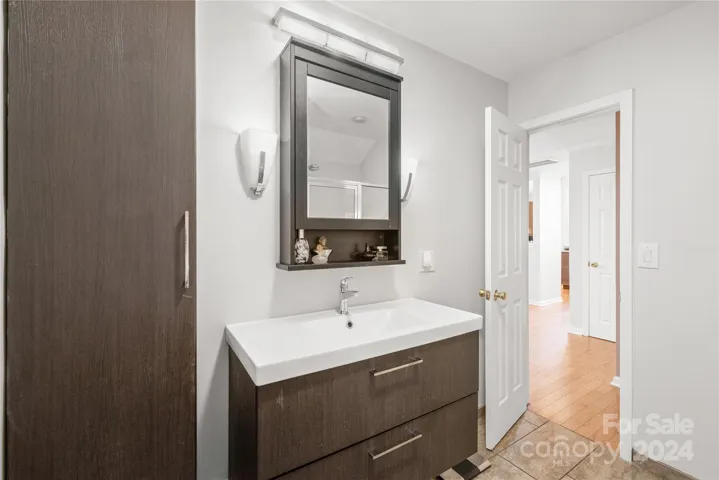 Primary bathroom on the MAIN floor with renovated cabinets, designer lights and tile floors.