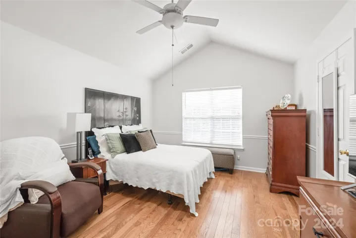 Primary bedroom on the MAIN Level with vaulted ceilings, hardwoods, fresh paint and walk-in closet.
