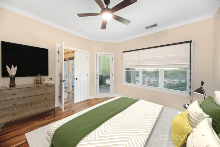 Primary bedroom (virtually staged) with double doors, custom shades and access to the covered balcony.