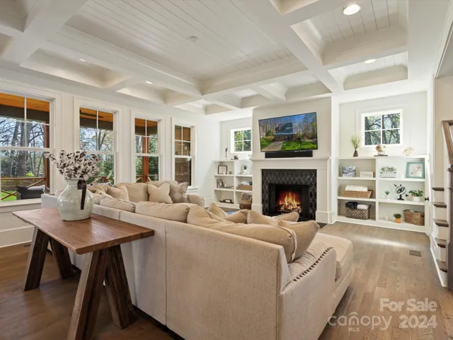 Living room with custom coffered ceilings, gas fireplace, custom built ins, and plenty of natural light.