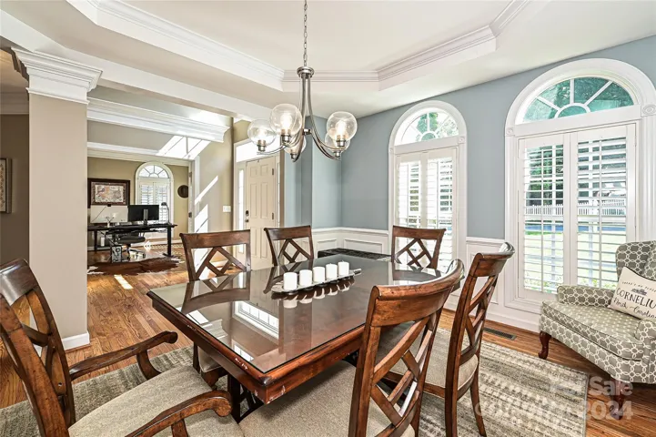 A bright and airy Dining Room features an updated light fixture and Plantation Shutters.