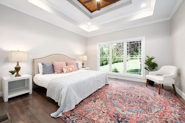 Main level primary bedroom with tray ceilings and garden views