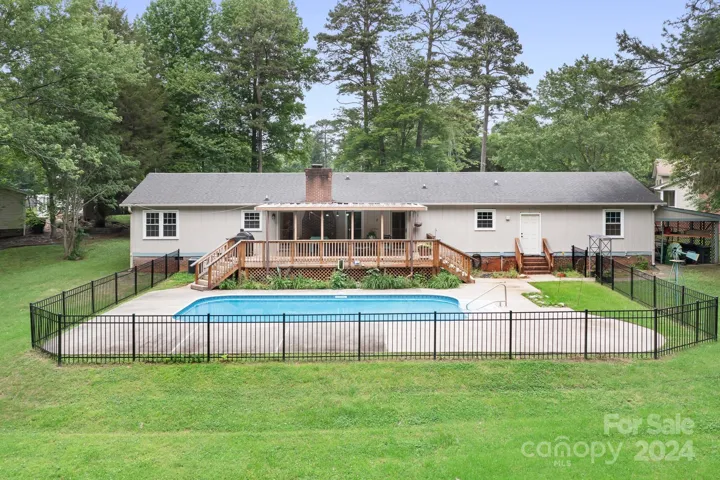 Pool area has extra patio space for a table and chairs.  Iron Fence and backs to trees.