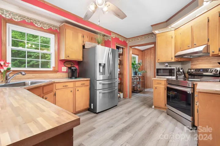 Kitchen area with Newer Stainless Refrigerator that Conveys. Window overlooks backyard with pool and trees
