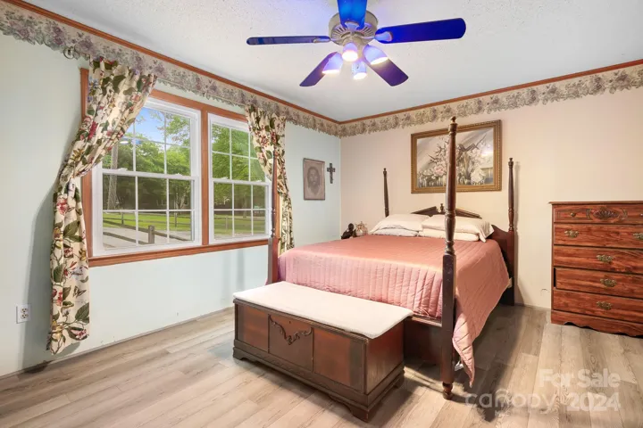 Primary bedroom with large windows overlooking front yard and cul-de-sac area.