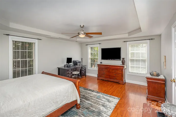 Primary Bedroom with tray ceiling and laminate flooring