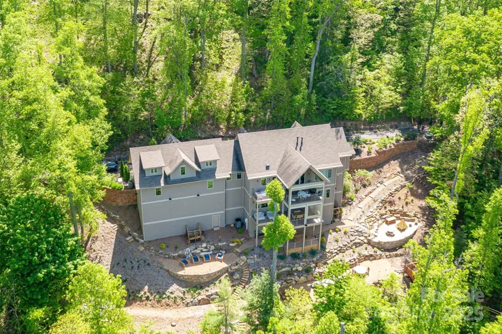 Soak in the seasons on multiple covered porches with retractable screens, decks & showstopping outdoor hardscape terraced yard. Send dinner down the exterior dumbwaiter before dining at the expansive teak table overlooking stunning sunset hues. Count the stars while roasting marshmallows in the cauldron fire pit. Playhouse, multiple seating areas and raised garden beds round out features.