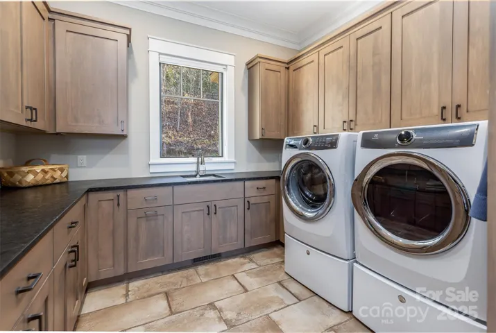 Laundry room has hall tree/drop zone spaces in addition to maple cabinetry and cast iron porcelain sink.