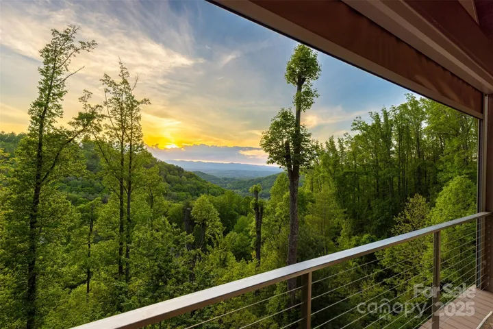 Long-range western views from this main level deck featuring cathedral ceilings, retractable screens, Azek maintenance-free decking and stainless steel cable railing.