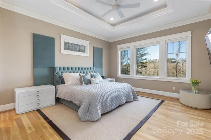 The primary suite has lovely tray ceilings with layered crown molding. Experience those long range views from bed.