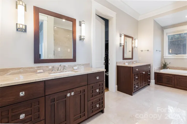 Primary en suite bath features radiant heated marble tile floors, dual vanities, soaking tub, walk-in closet with custom build-ins and linen closet.