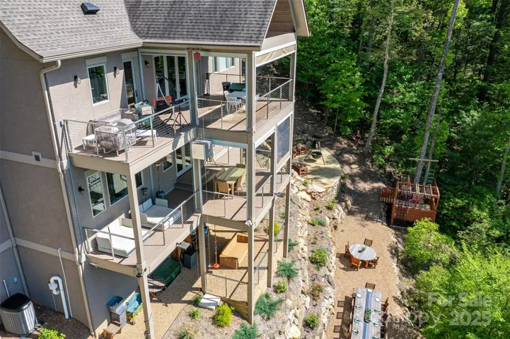Soak in the seasons on multiple covered porches with retractable screens, decks & showstopping outdoor hardscape terraced yard. Send dinner down the exterior dumbwaiter before dining at the expansive teak table overlooking stunning sunset hues. Count the stars while roasting marshmallows in the cauldron fire pit. Playhouse, multiple seating areas and raised garden beds round out features.