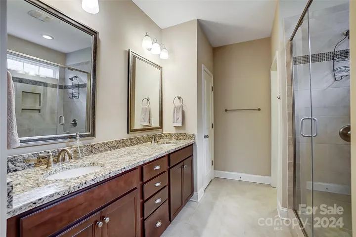 Primary bath with dual vanities, granite counters, tile flooring, huge walk in shower and closet