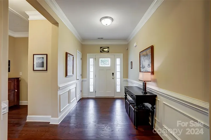 Bright and open floor plan boasting beautiful flooring, rich molding, wainscoting, and tons of natural light