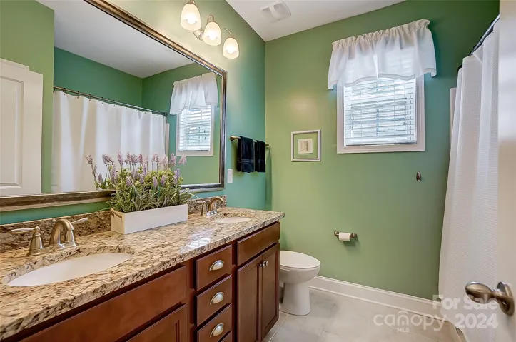 Full bath with dual vanities, tile floors, and tub