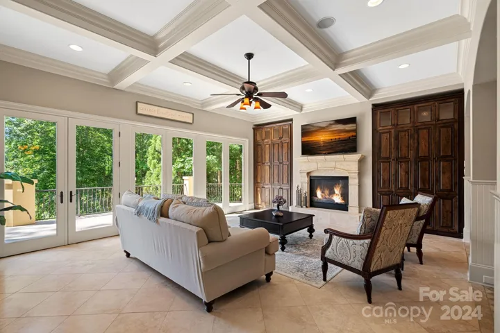 Gorgeous Great Room with views to the lake, gas fireplace, floor-to-ceiling built-ins, and beautiful coffered ceiling