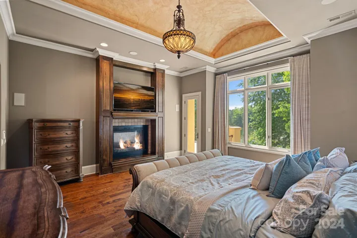 Primary Suite with lake views, gas fireplace, beautiful coved ceiling, and convenient dry bar. Not pictured - Large walk-in closet with washer/dryer hookup.