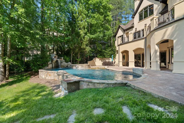 Back yard with lake views, terrace, and in-ground pool with whirlpool and waterfall feature.