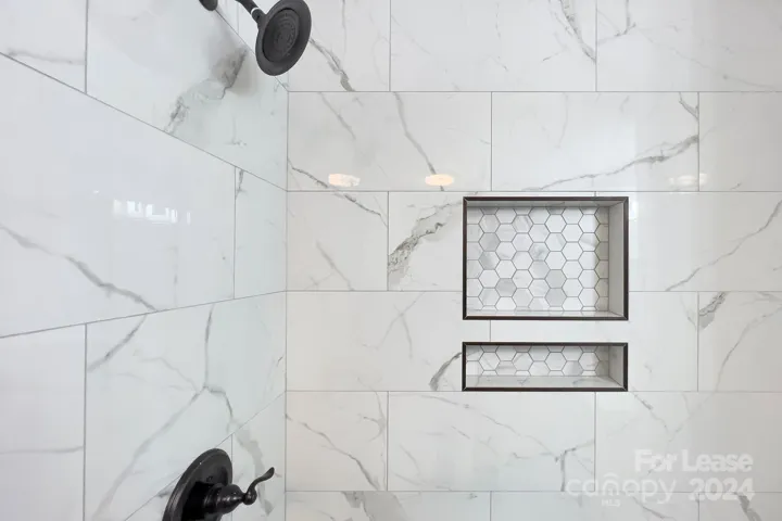 The surround shower in primary bathroom with frameless glass door