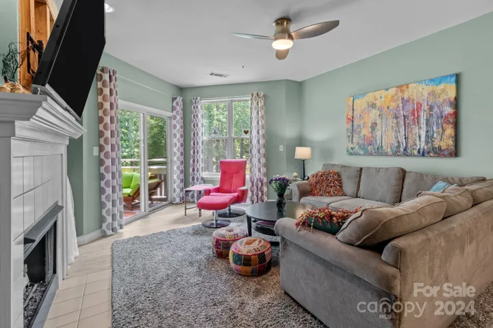 Open concept living room has large windows and gas log fireplace. Entrance to the primary bedroom is off the living room. The covered deck invites guests to enjoy the outdoors.