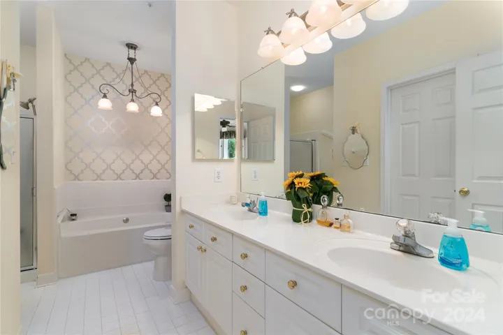 Spacious tiled primary Bath with dual sink vanity, tub, and shower