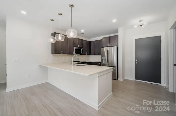 Kitchen has quartz counters, tile backsplash, stainless steel appliances, and pretty pendant lights!