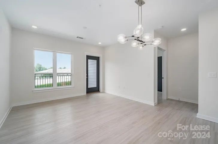 Open dining and living area with pretty light fixture and access to covered balcony.