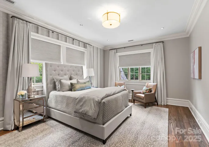 Secondary bedroom with  hardwood floors and custom cut area rug and window treatments.