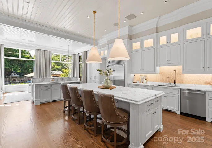 Dual island design opens to additional dining and seating space with; fireplace overlooking the backyard and pool area.