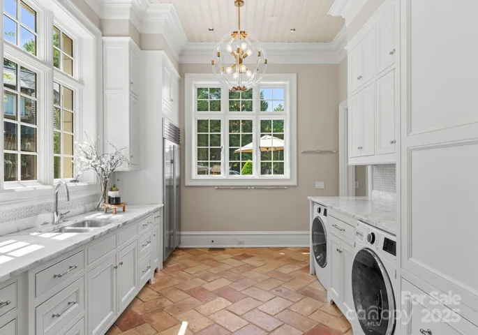 Scullery includes laundry and folding station, additional floor to ceiling cabinetry, and secondary built-in Subzero Refrigerator.