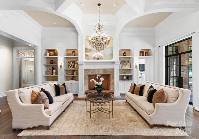 Library offers built-ins with backlighting, Visual Comfort sconces, and oversized French imported fireplace.