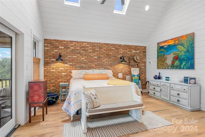Primary bedroom with soaring ceiling, antique brick wall and its own screened in porch with a Mountain View!